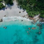an aerial view of a beach with blue water